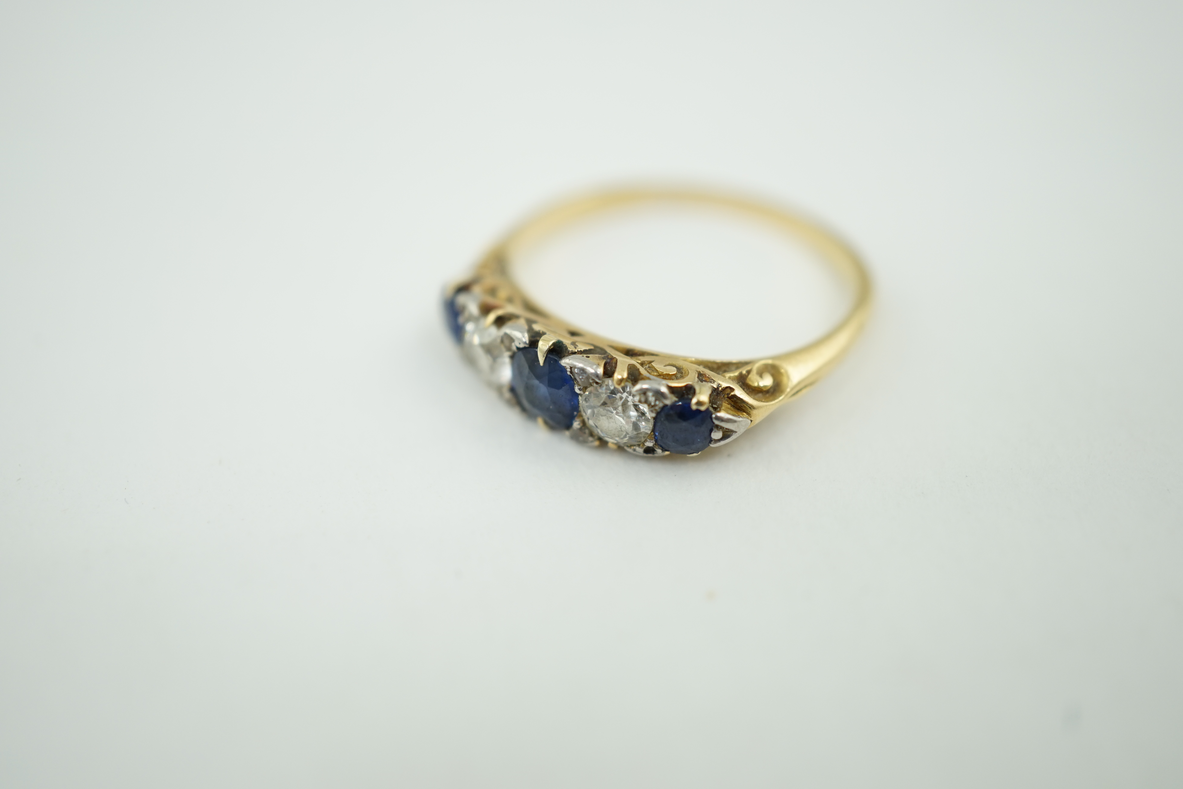 A gold, three stone sapphire and two stone diamond set half hoop ring